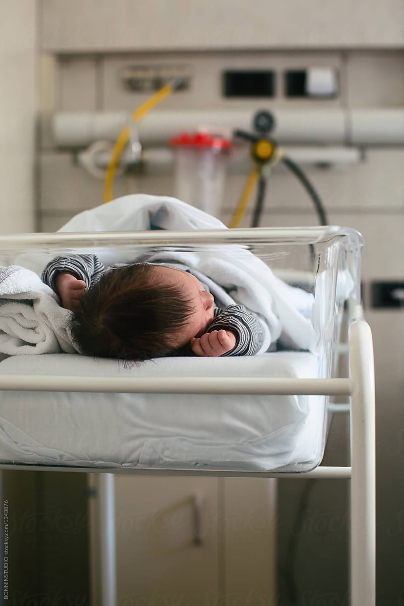 Newborn baby boy sleeping in a hospital room.