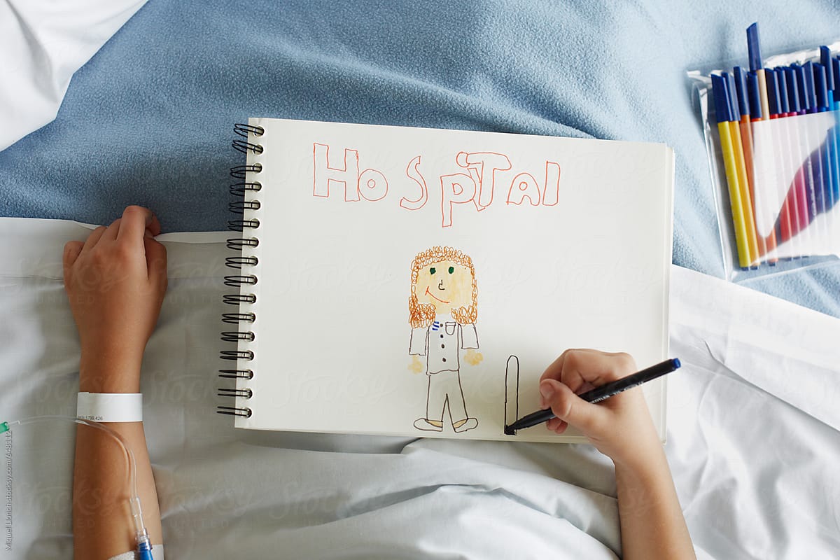 Patient child in hospital bed  writing and drawing on sketchbook