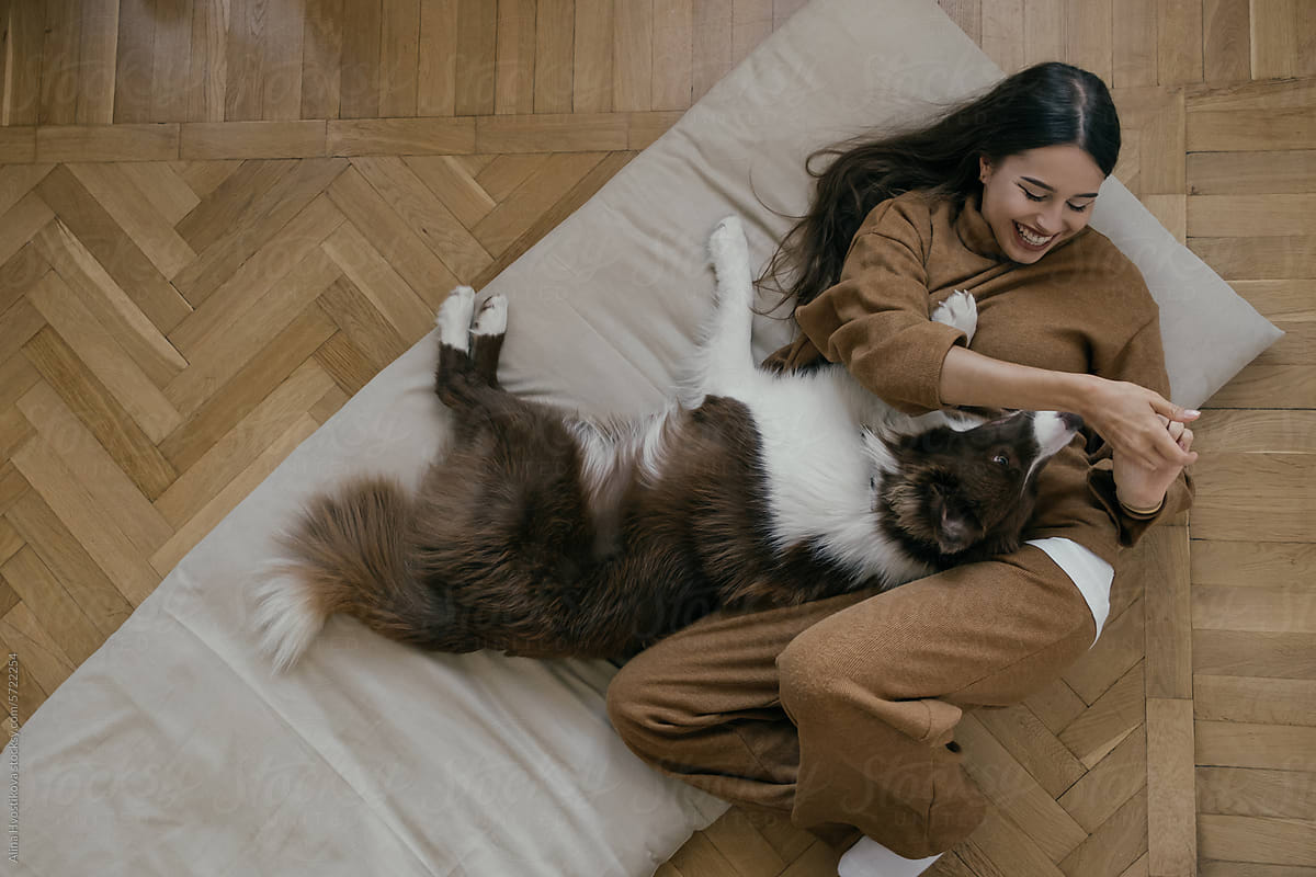 Happy young woman playing with Border Collie pet dog