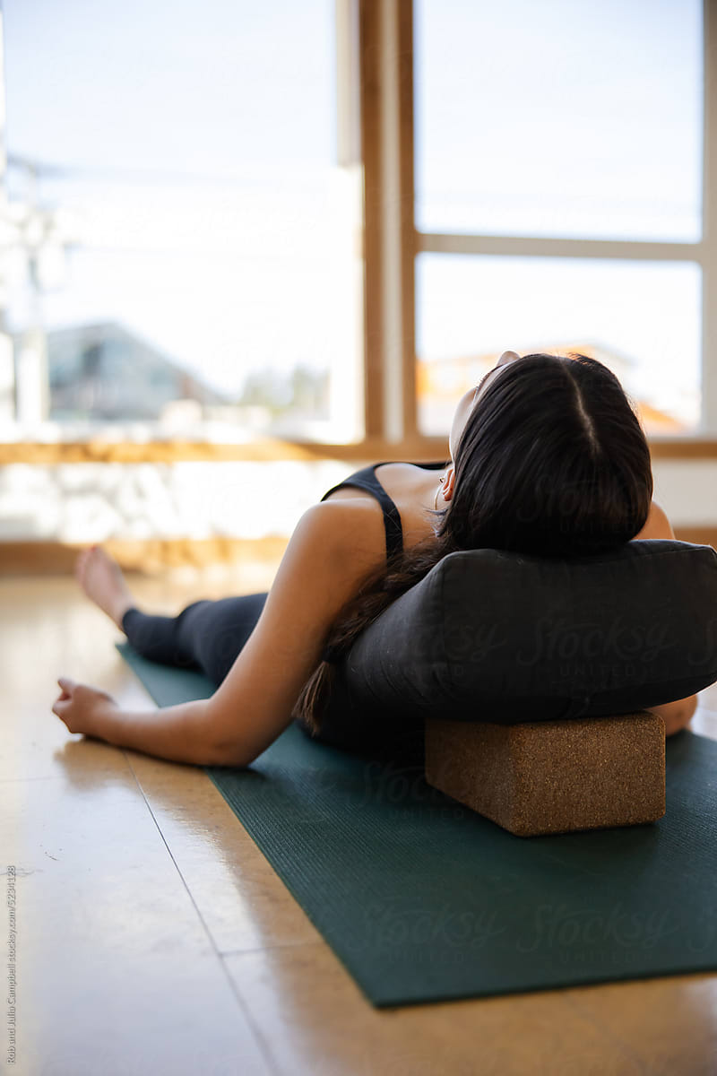 Woman in Shavasana pose with pillow.