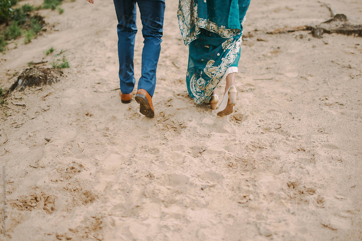 Indian bride and groom walking in the sand