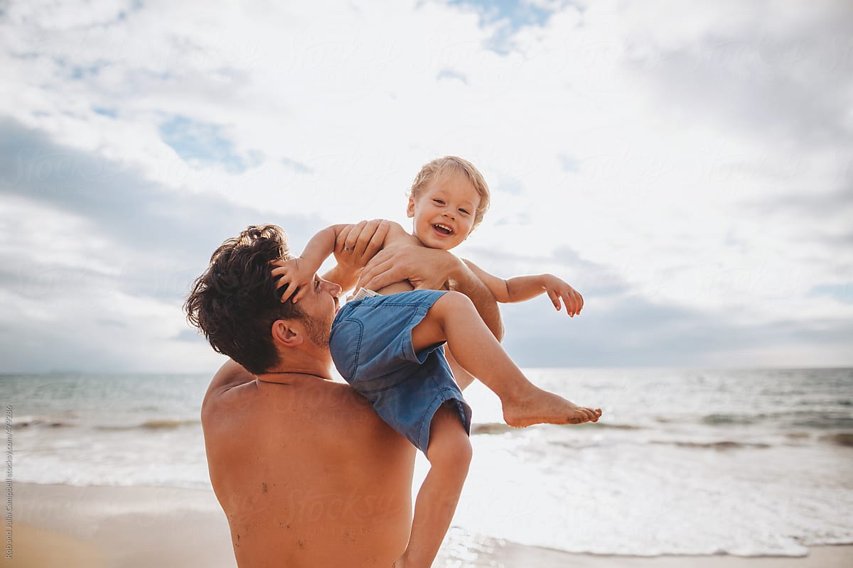 Young dad having fun with toddler son on tropical beach