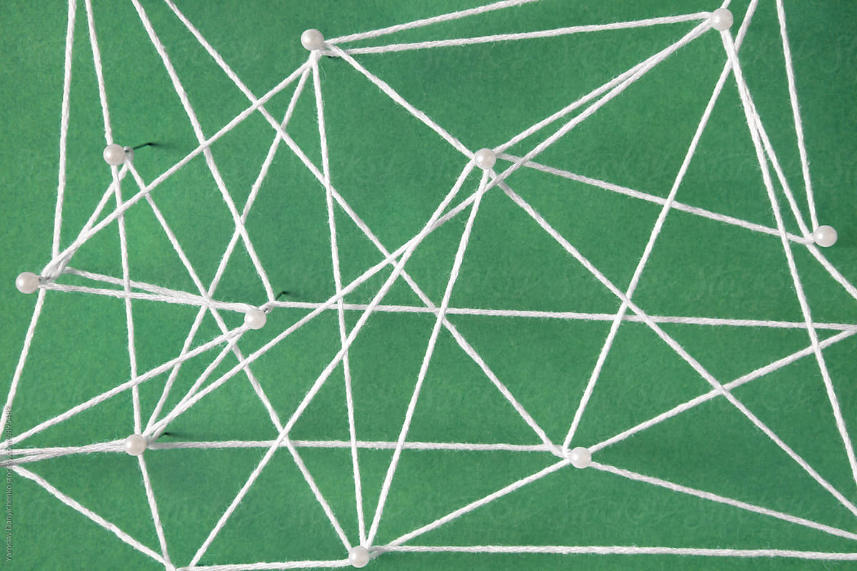 Top view of push pins connected with white string in on green paper