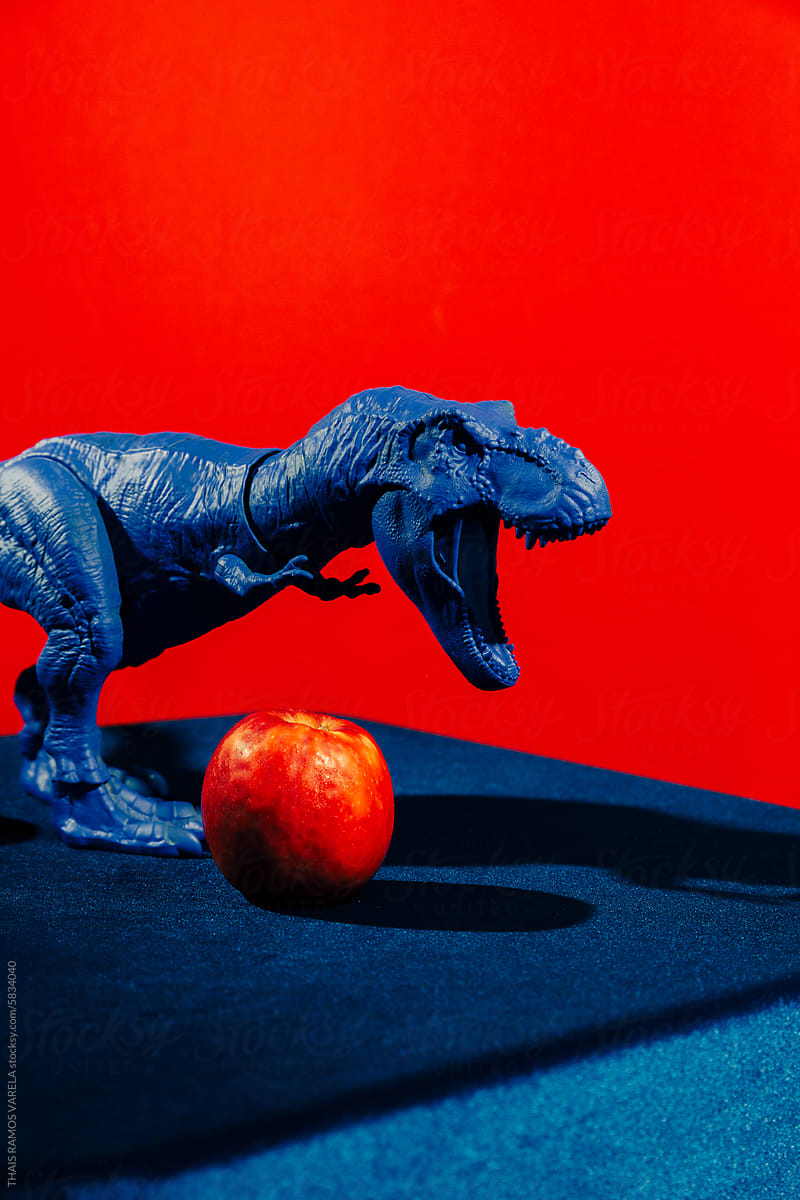 Blue Toy Dinosaur Positioned Next to a Red Apple
