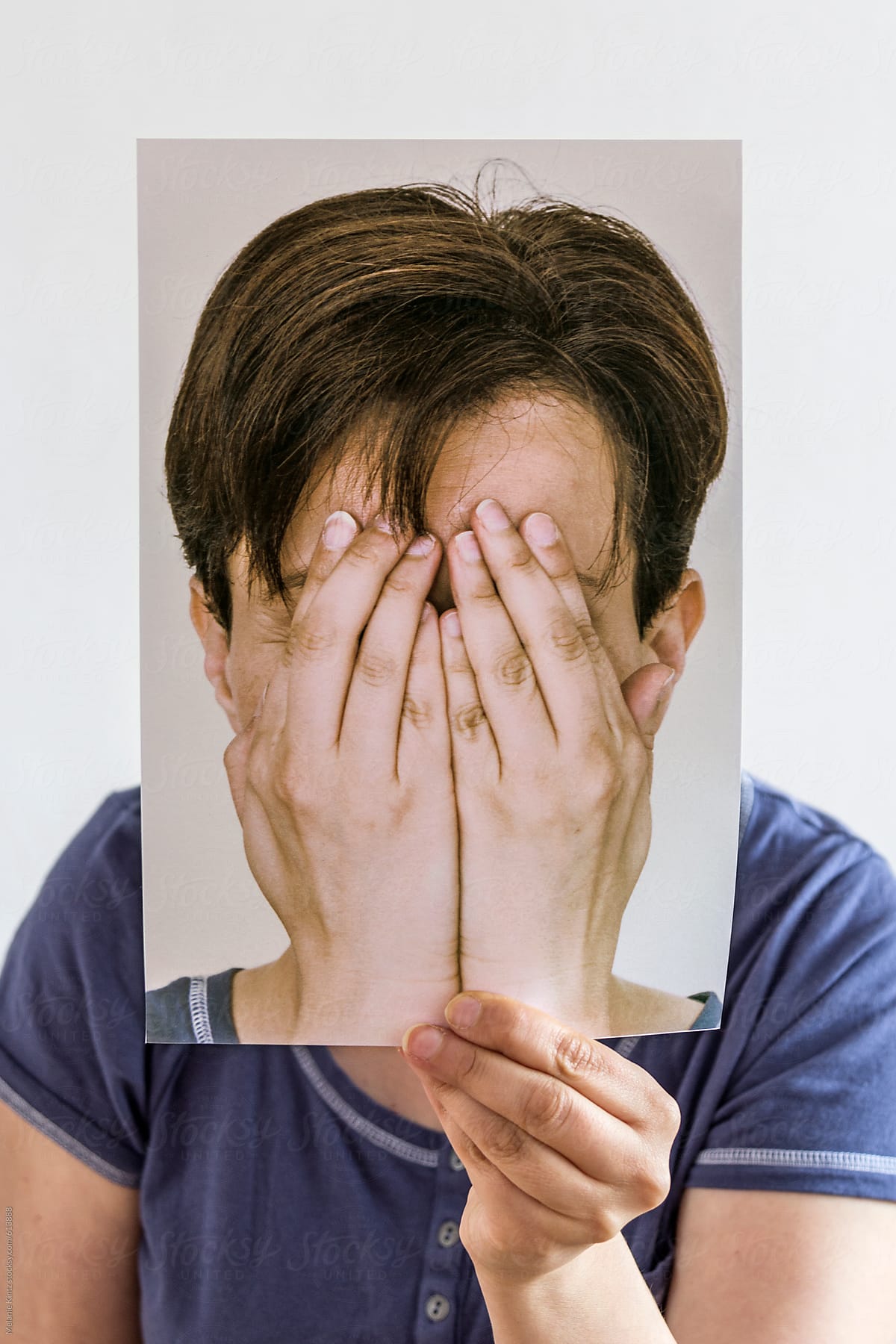person hiding behind an image of her hiding behind her hands
