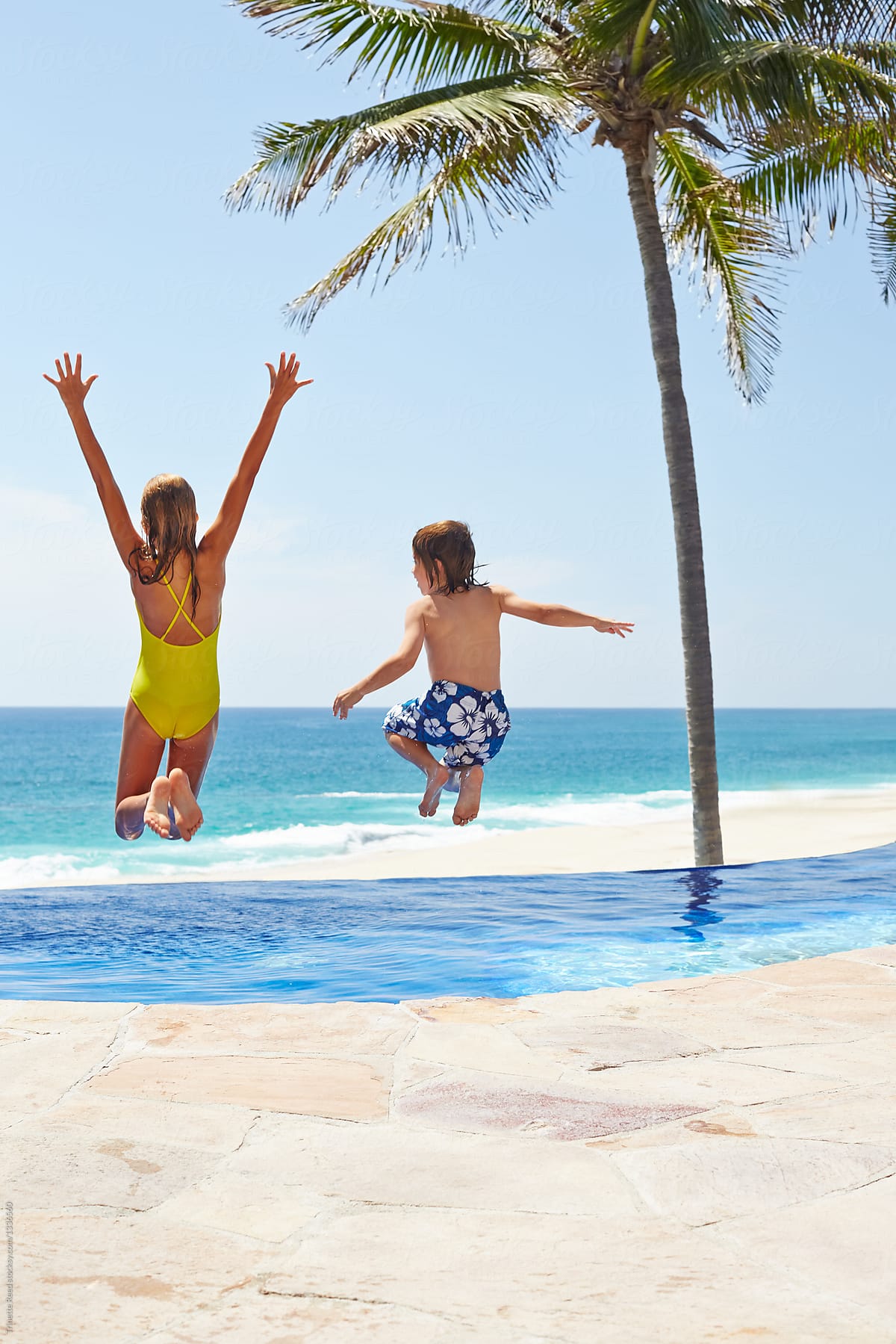 Kids running and jumping into a pool at luxury resort