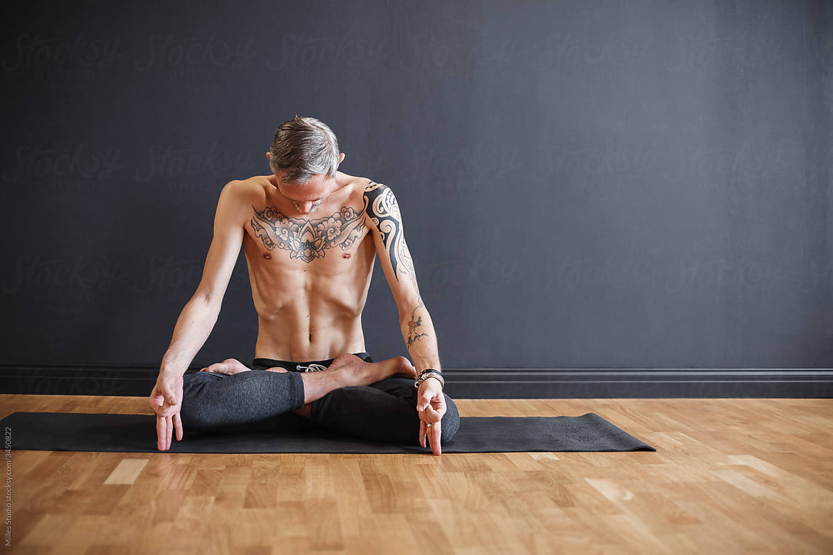 Tattooed man doing respiratory exercise and meditating