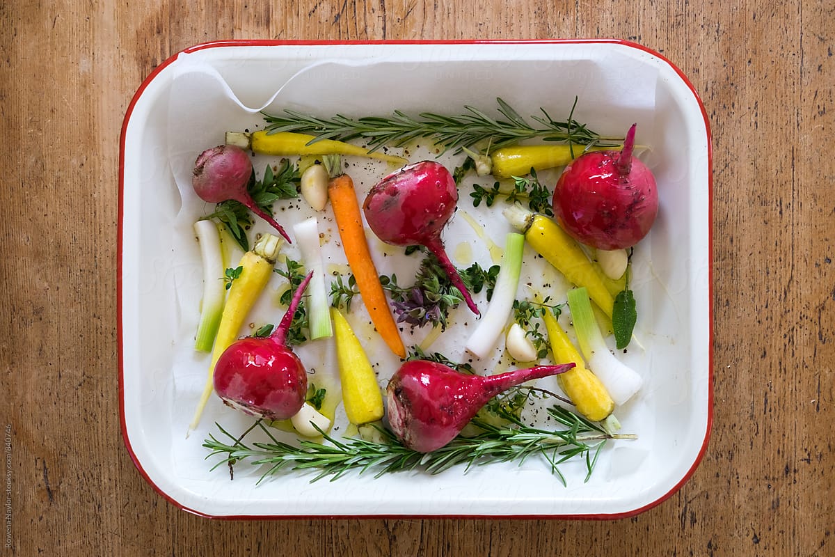 Roasting tray of fresh root vegetables and herbs