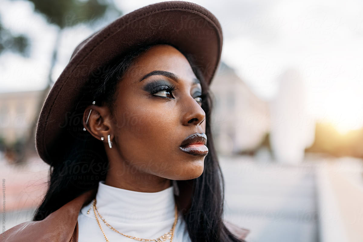 Serious black woman in leather coat and hat