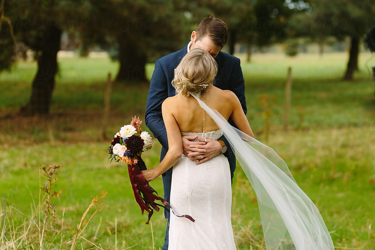 Wedding Couple Embracing with Veil Flowing