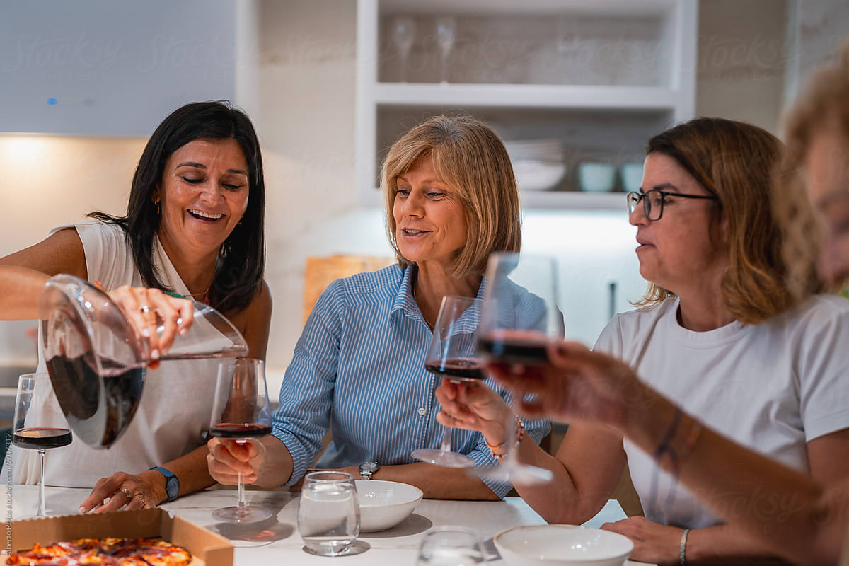 Happy female friends drinking wine at home