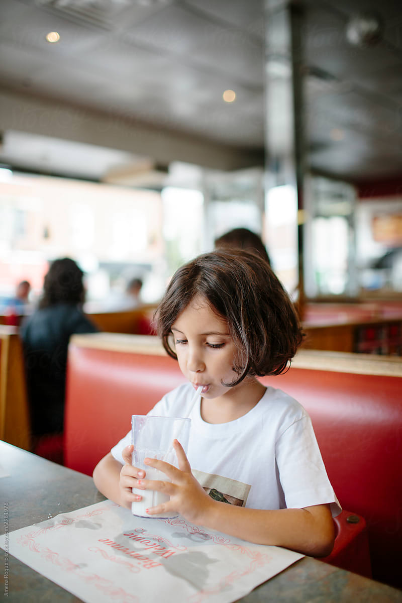 Kid drinking milk in a diner.