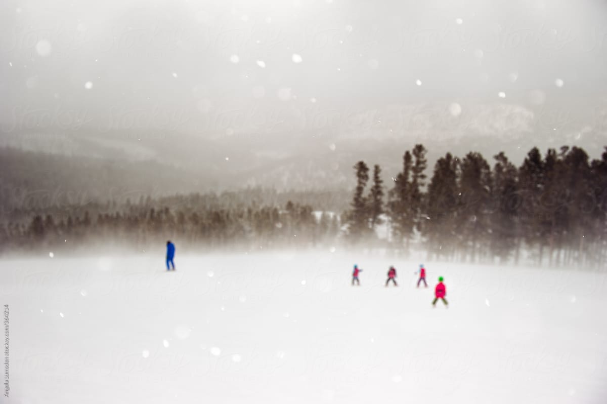 Four small children in ski school follow a ski instructor in a snow storm