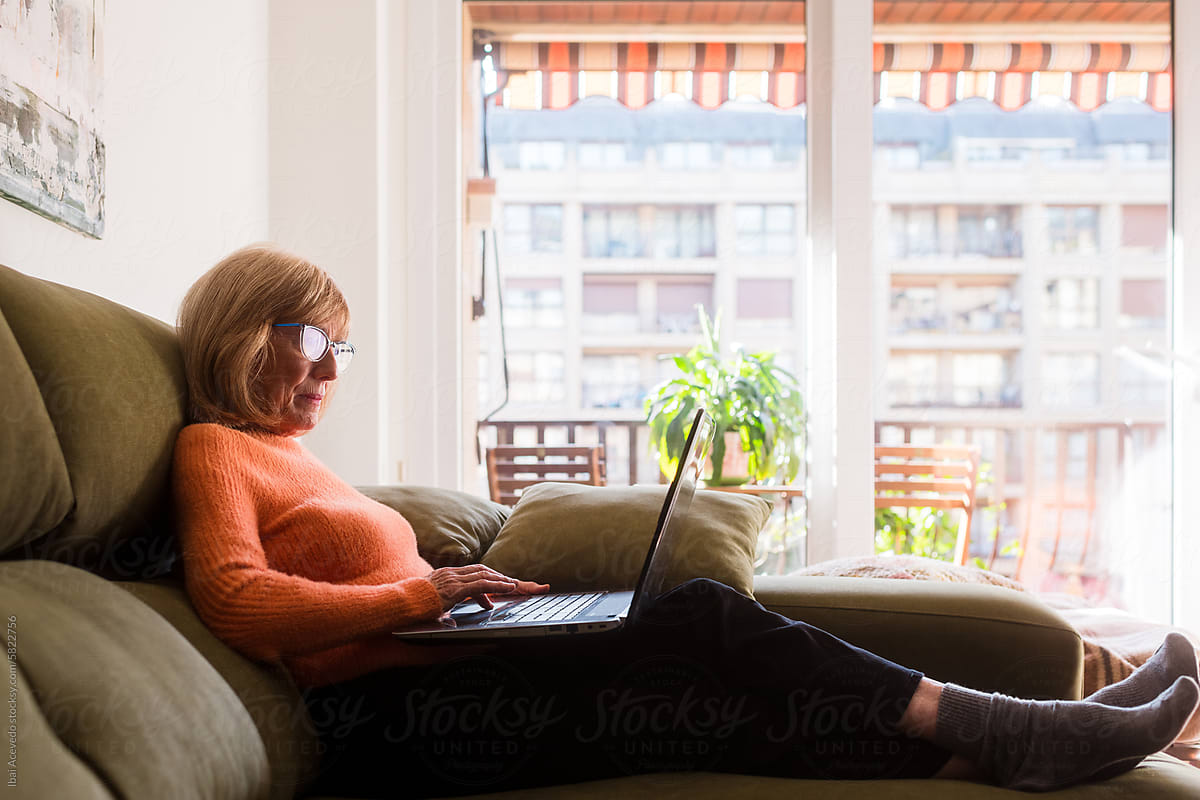 Relaxed woman checking online banking on sofa