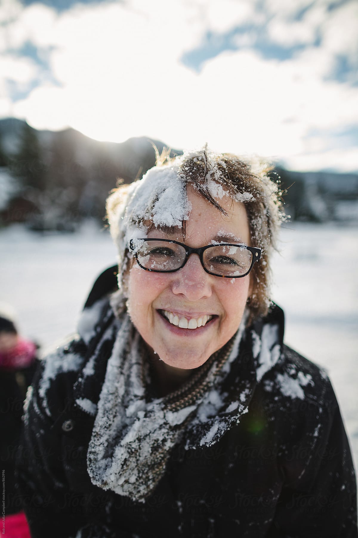 Happy mature woman covered in snow outside in winter (post snow fight)