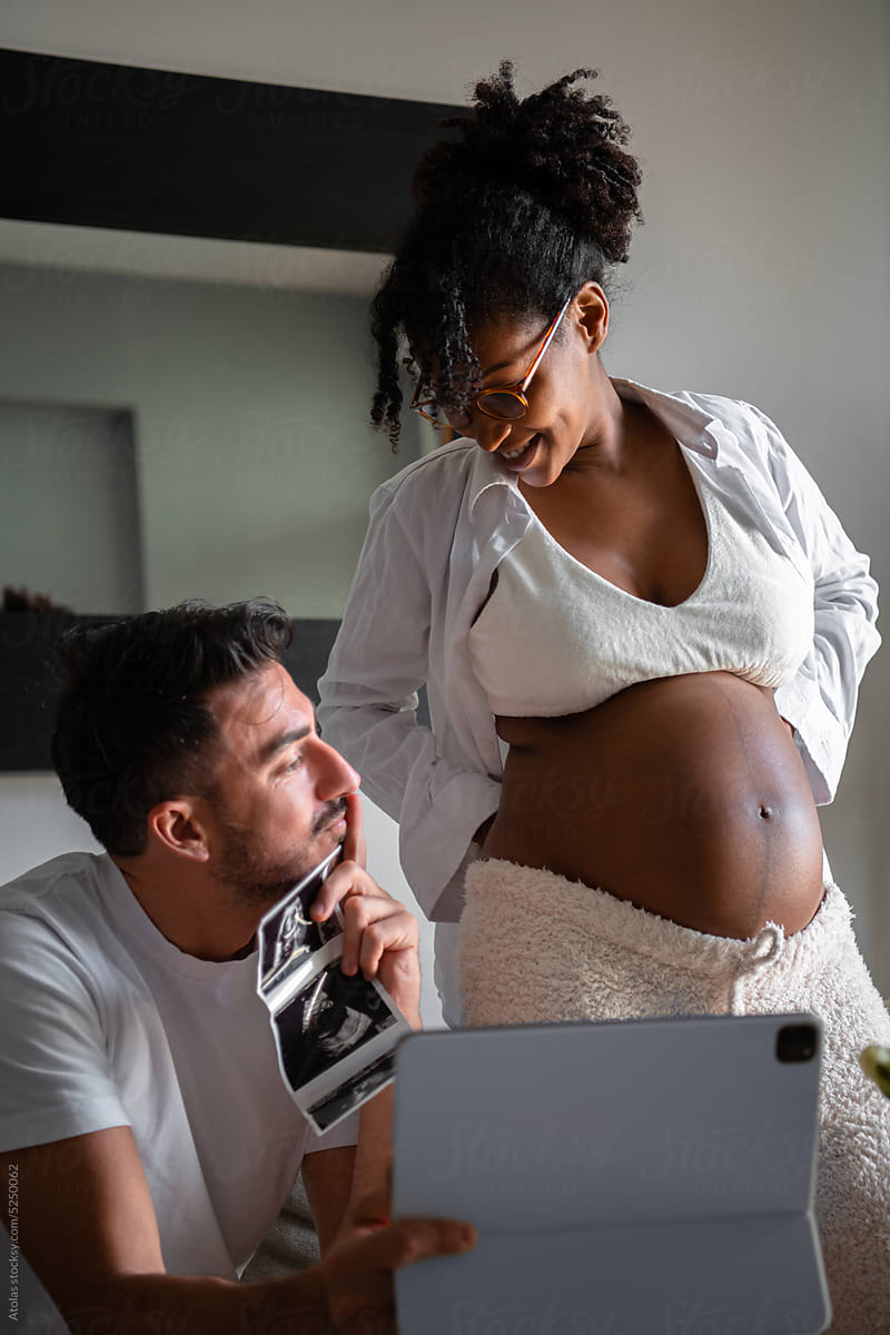 Happy pregnant couple showing ultrasound result on videocall