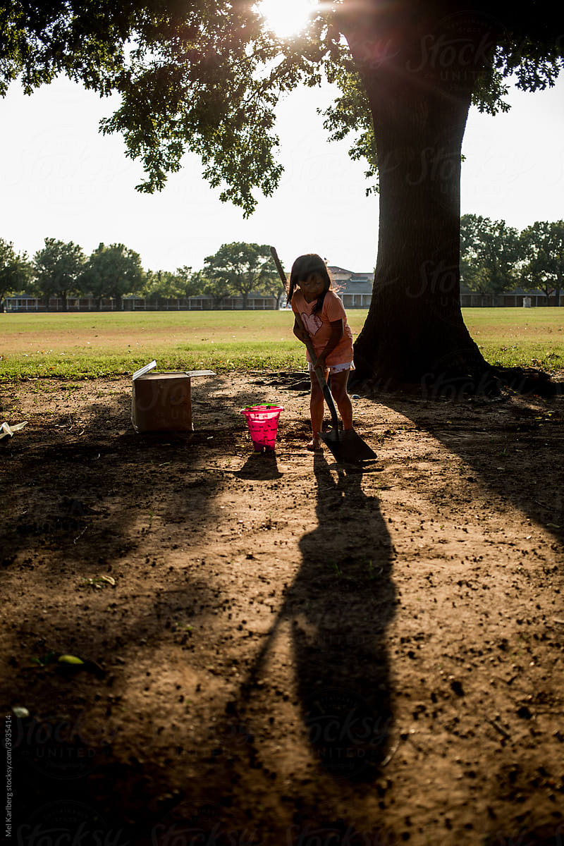 Young girl playing with dirt and bucket in a field