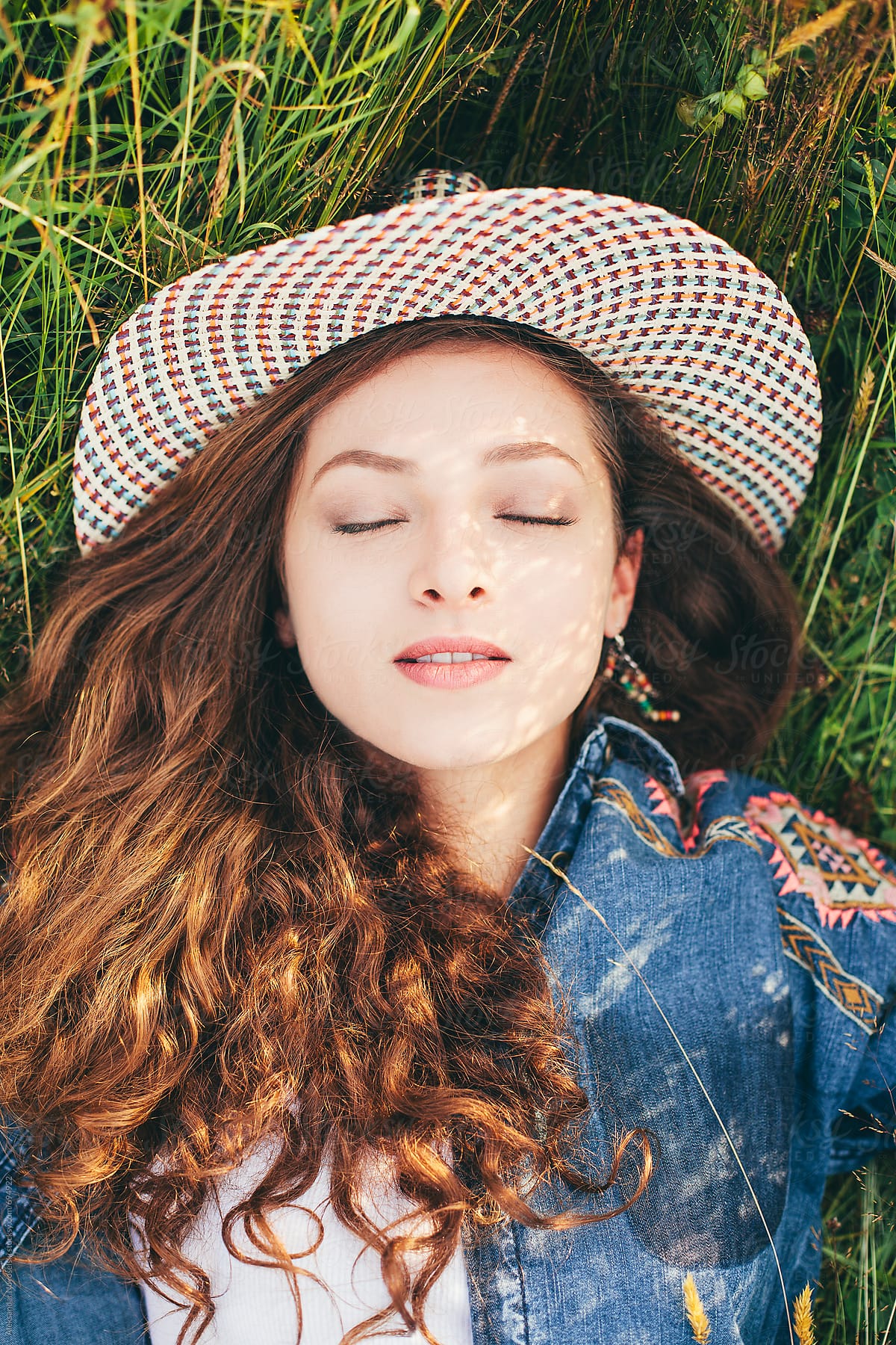 Sensual Portrait Of A Beautiful Woman With Hat Laying On The Grass Del Colaborador De Stocksy
