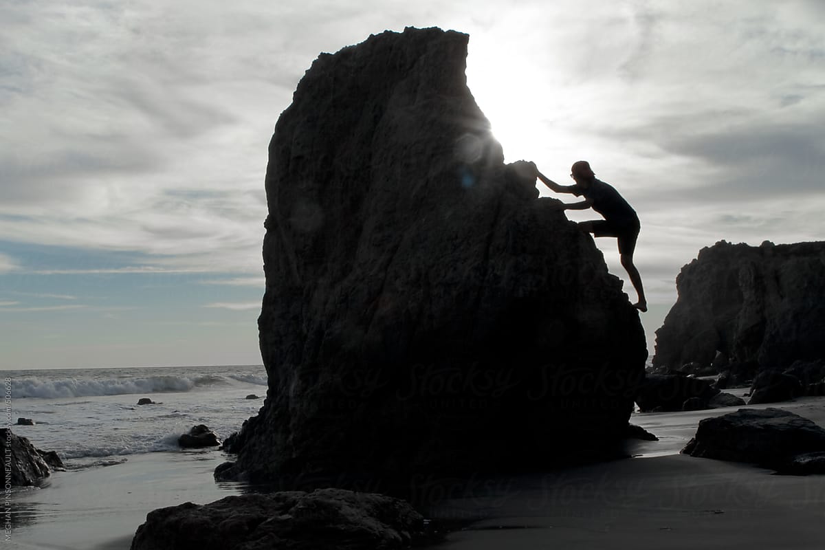 Man Climbing Up Rock Formation on the Beach
