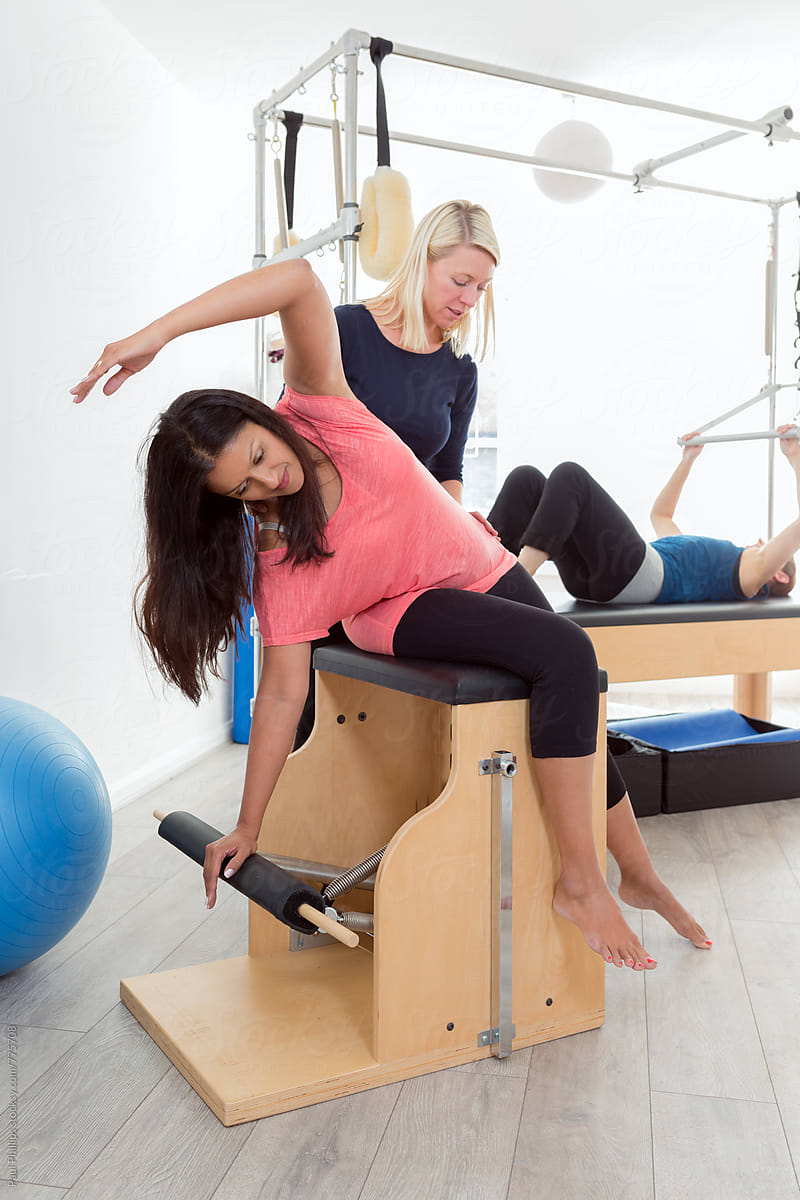 Pilates Exercise On The Wunda Chair With Instructor And Student by Stocksy  Contributor Paul Phillips - Stocksy