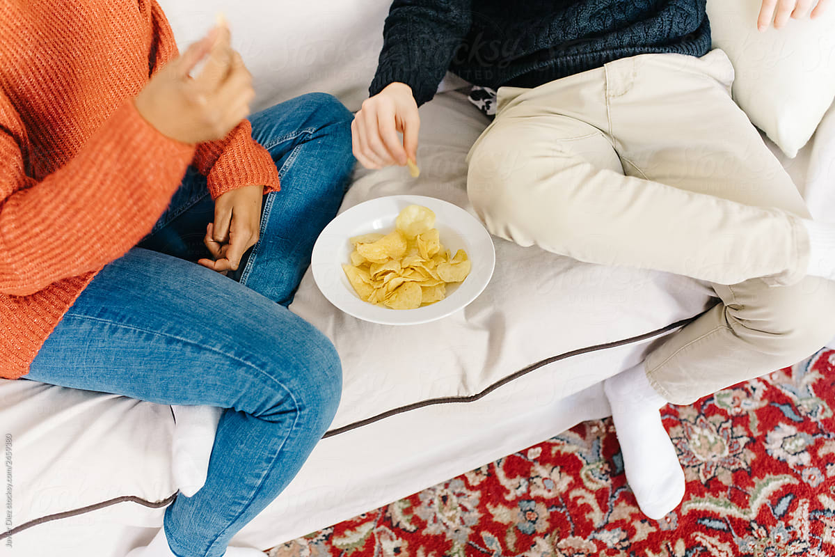 Friends eating chips on sofa