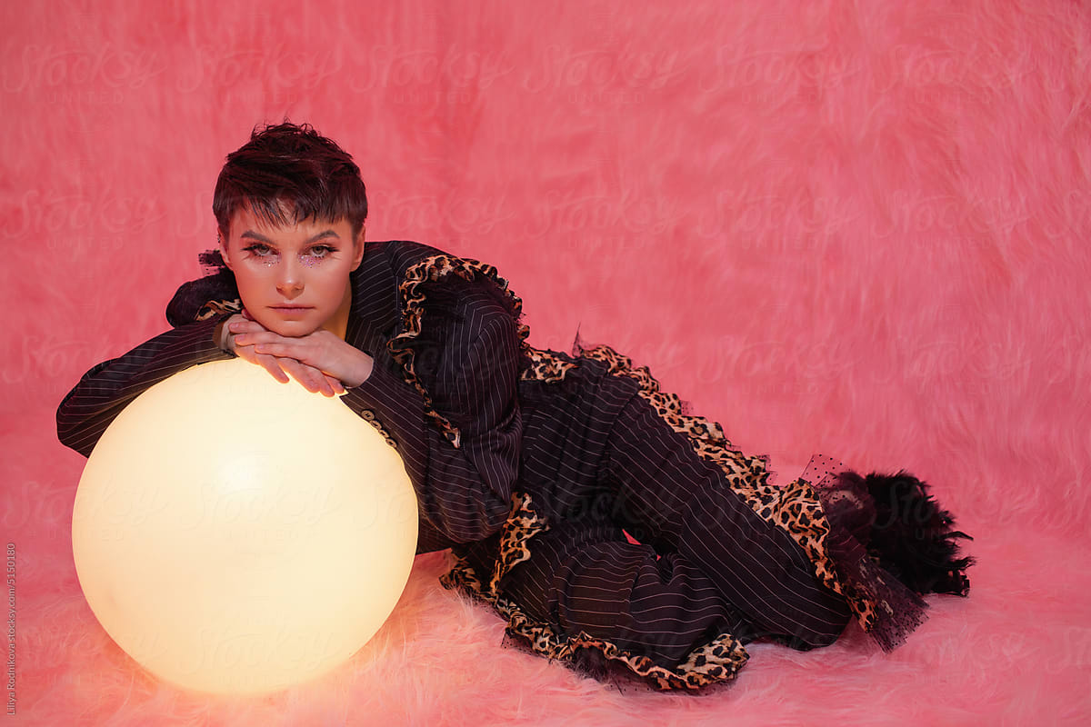 Eccentric woman with short hair posing in pink room