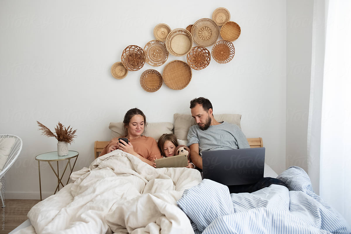 Family using gadgets on bed in morning