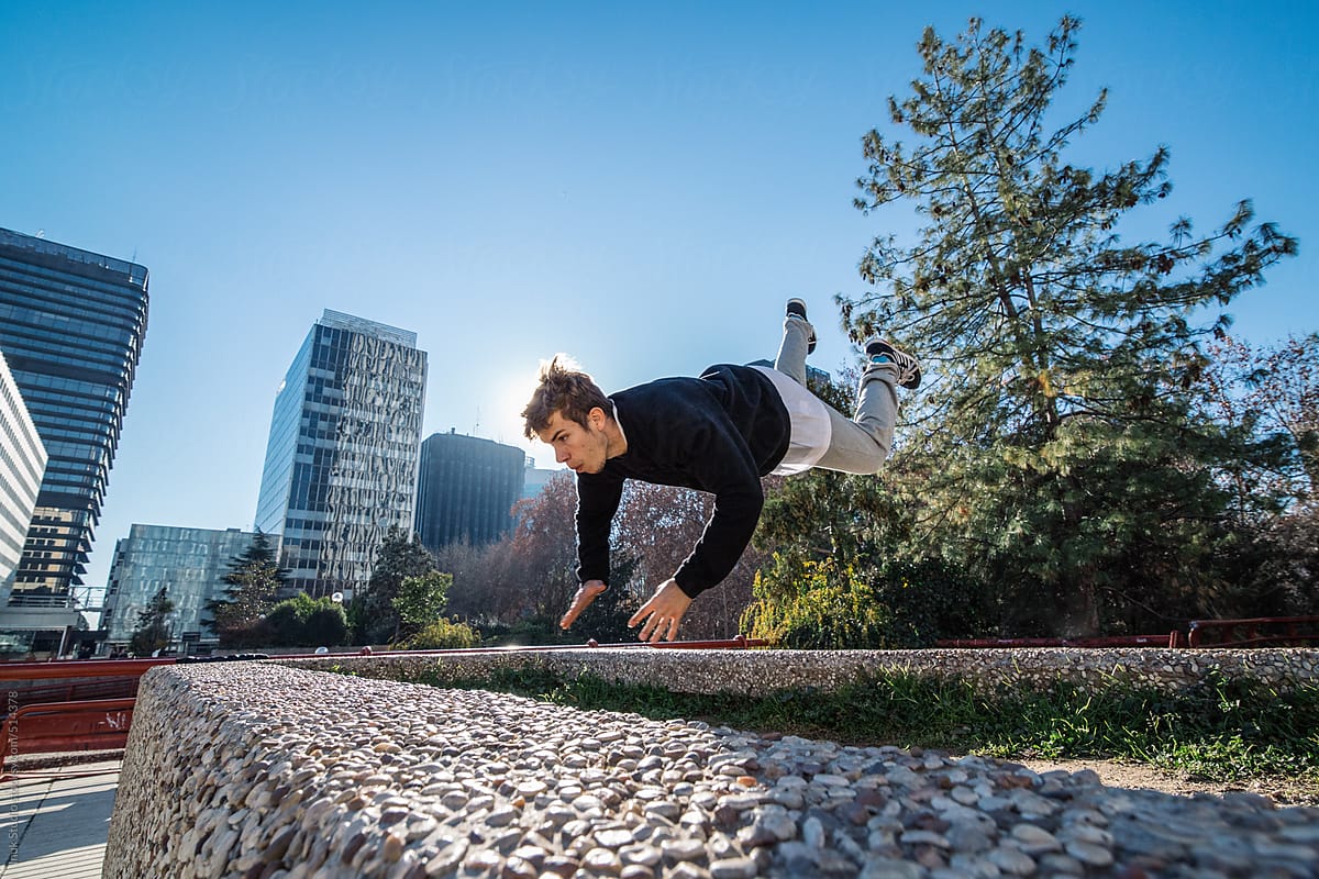 Man making a leap over a wall during a parkour training in a city