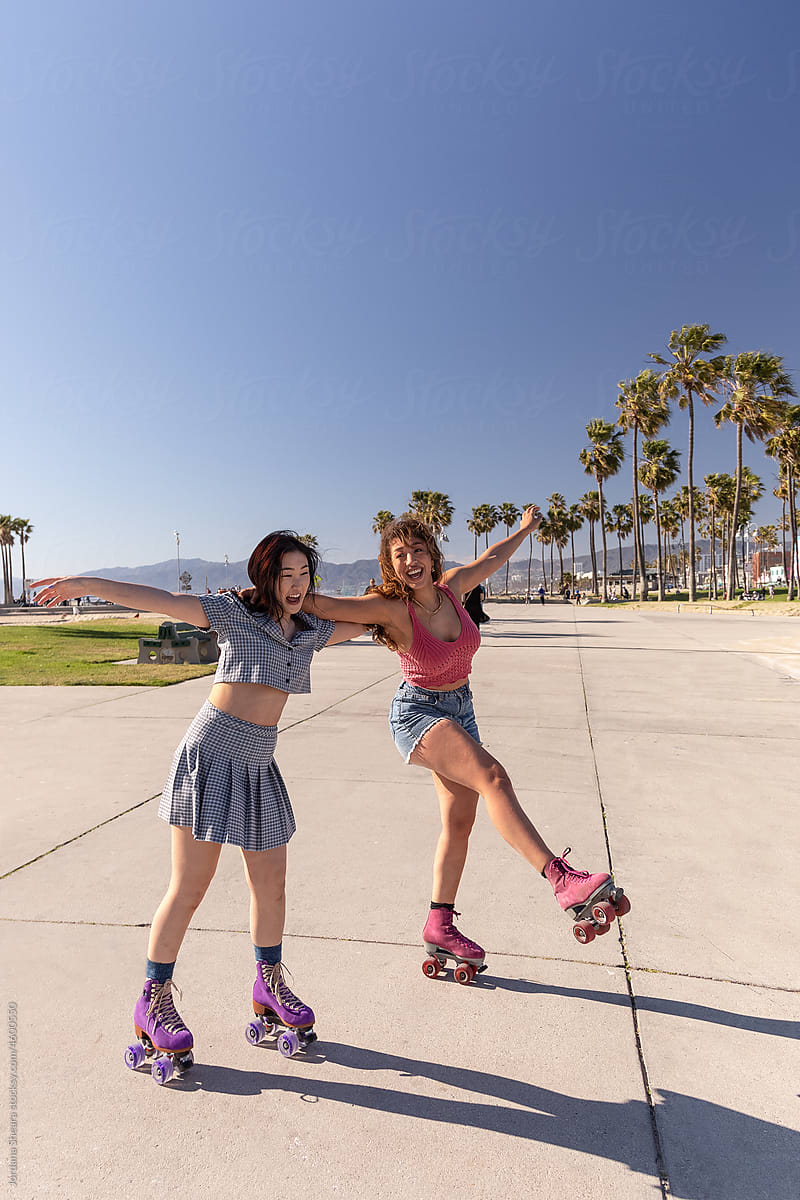 Gen-z friends having fun roller skating together by the beach