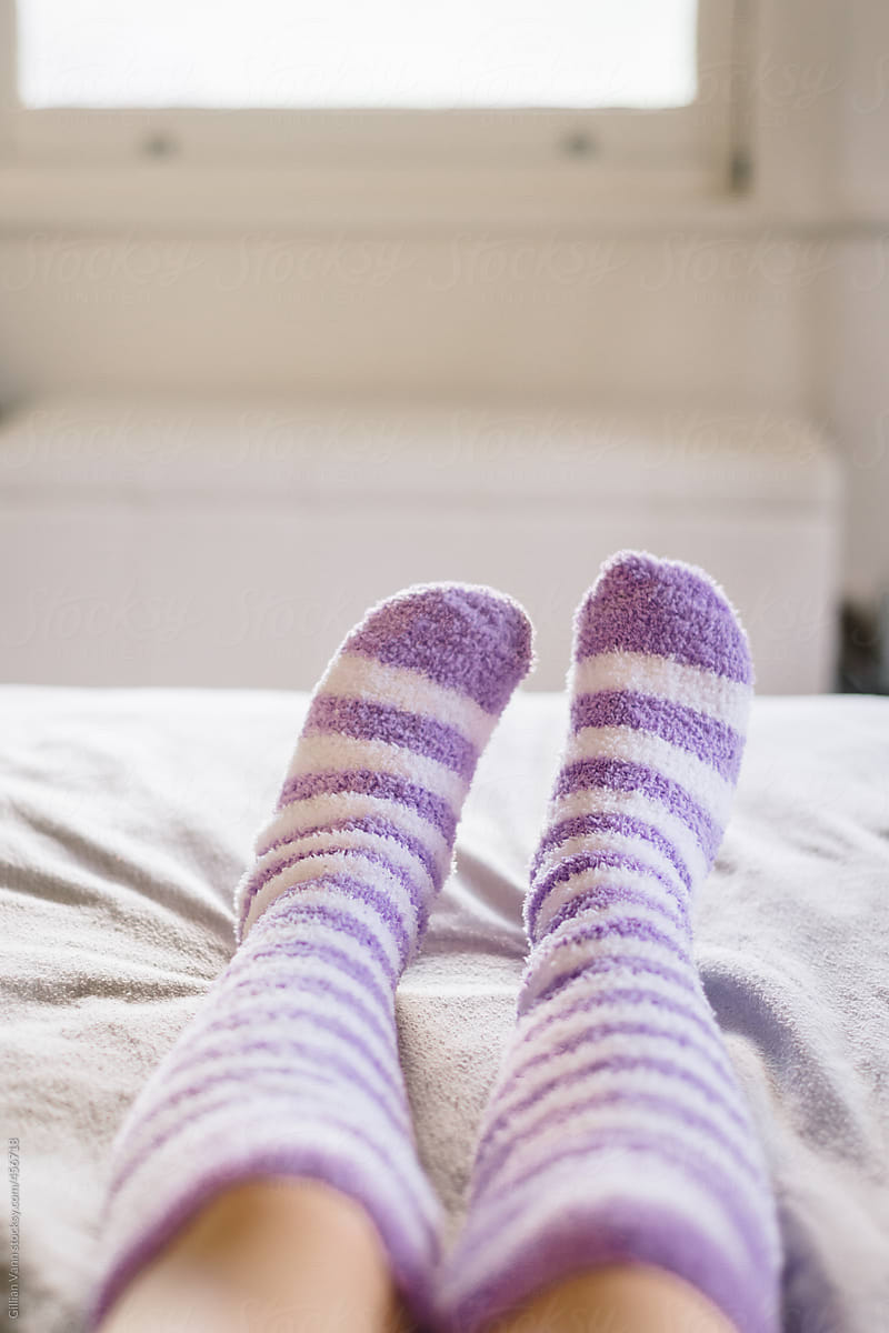 girl\'s feet in stripey socks on the bed