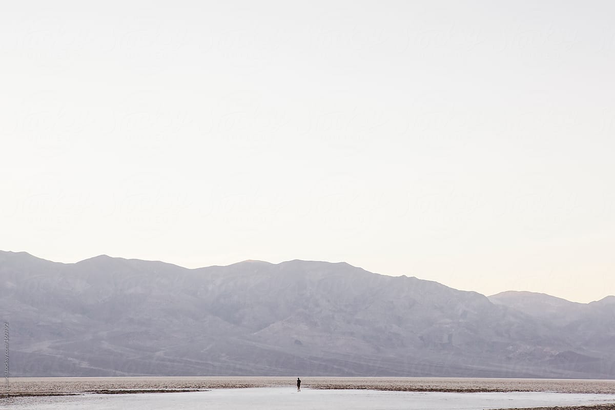 A photographer walks on the salt flats in Death Valley in the la