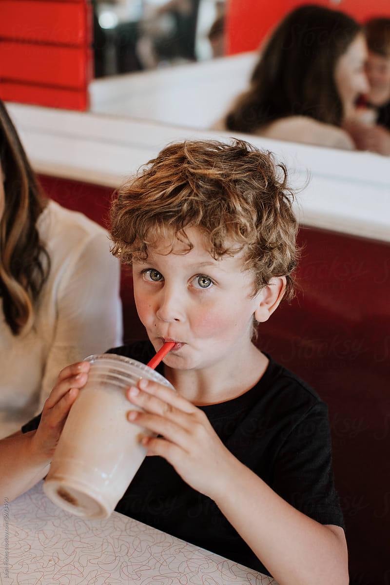 Young Boy Drinking Milkshake and Looking at Camera