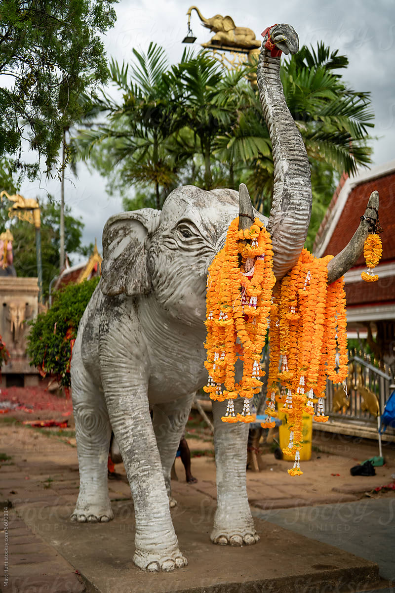 An elephant statue covered in marigold flowers at a temple in Thailand