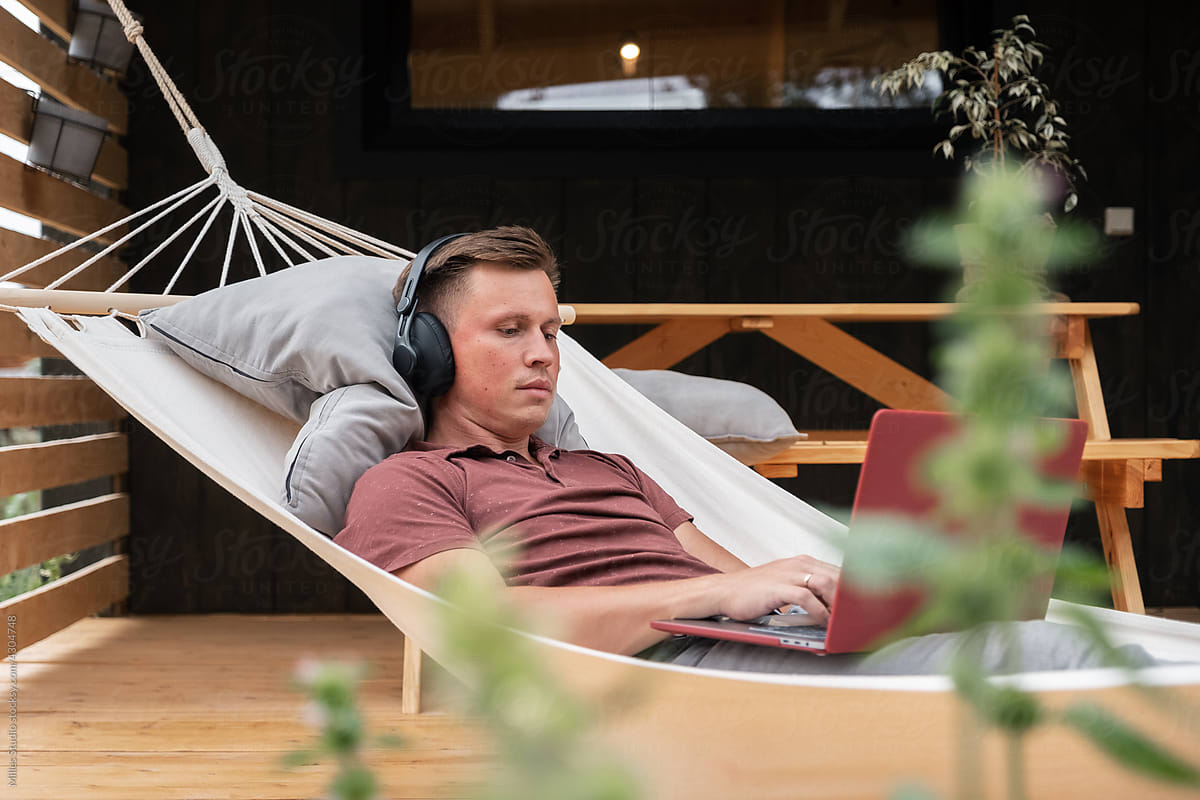Man browsing data on laptop in hammock