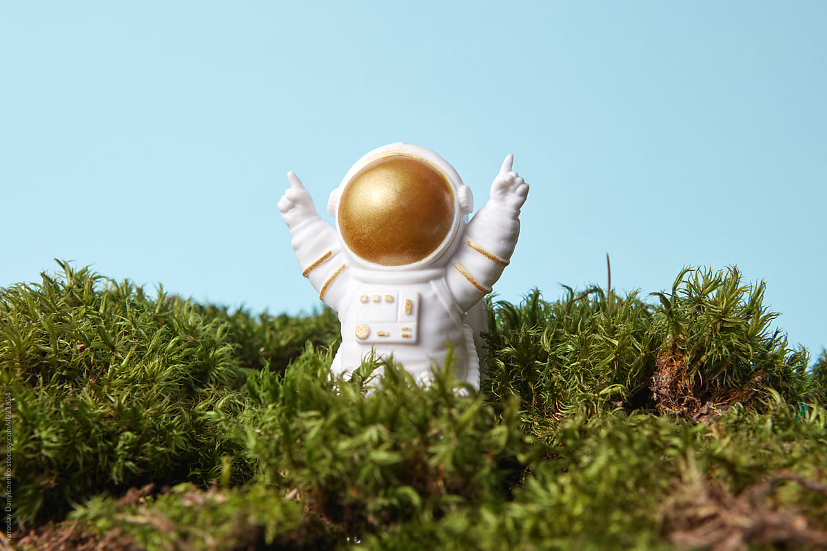 Toy astronaut sitting in moss