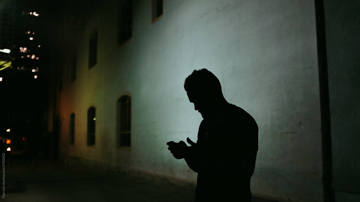 Silhouetted man checking his phone