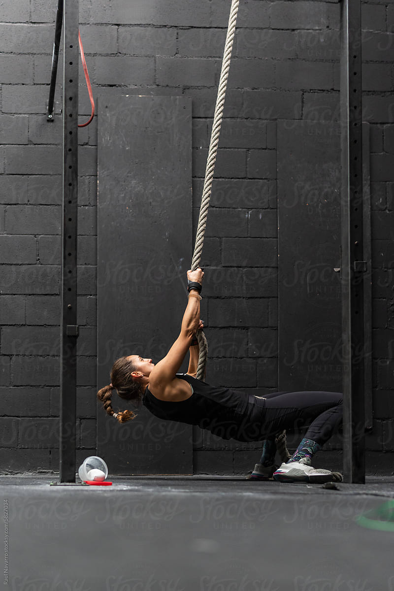 woman training rope climbs at the crossfit gym.