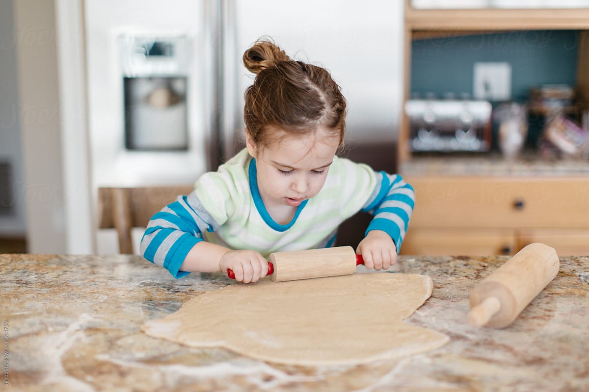 Toddler rolling dough with a rolling pin