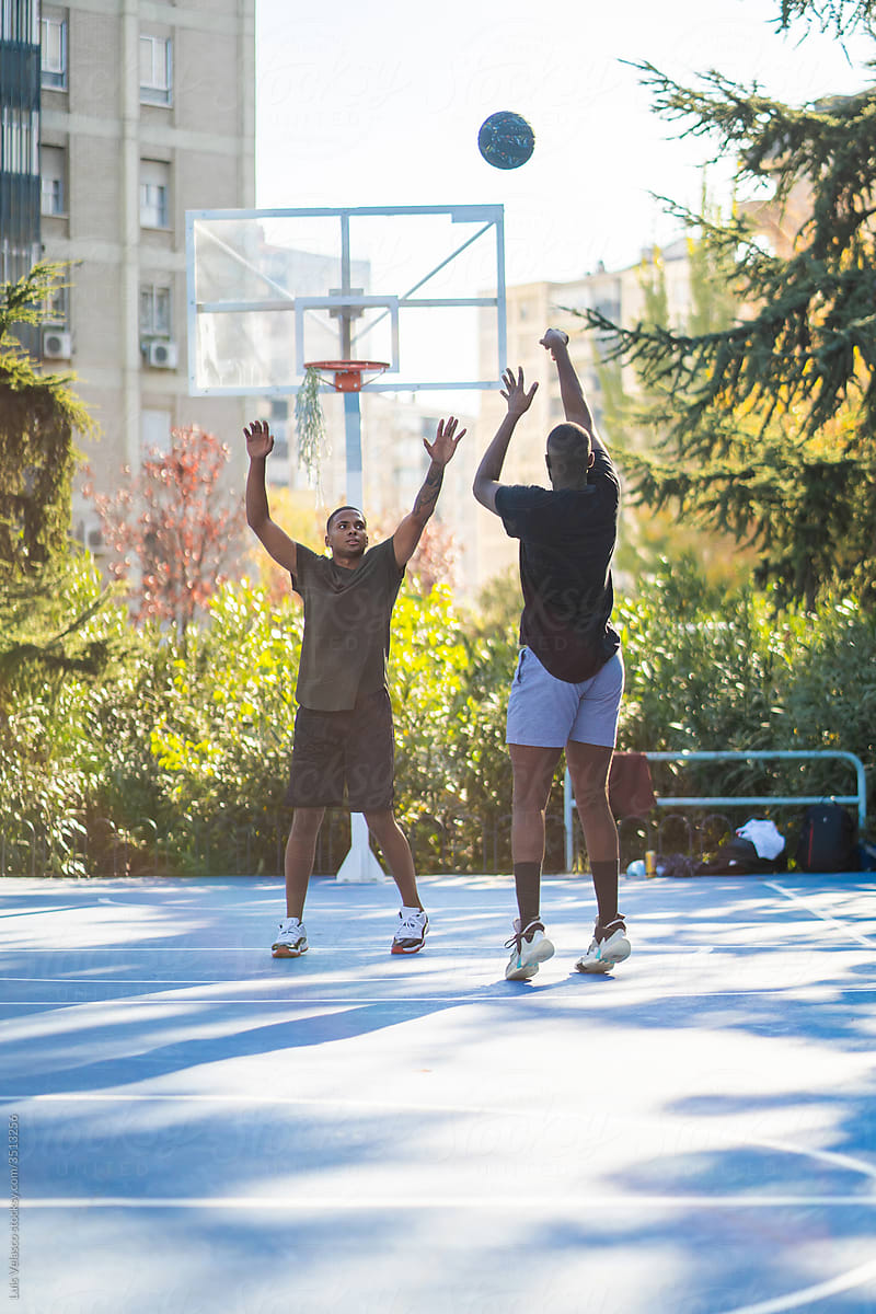 Two Black Boys Playing Basketball Outdoors.