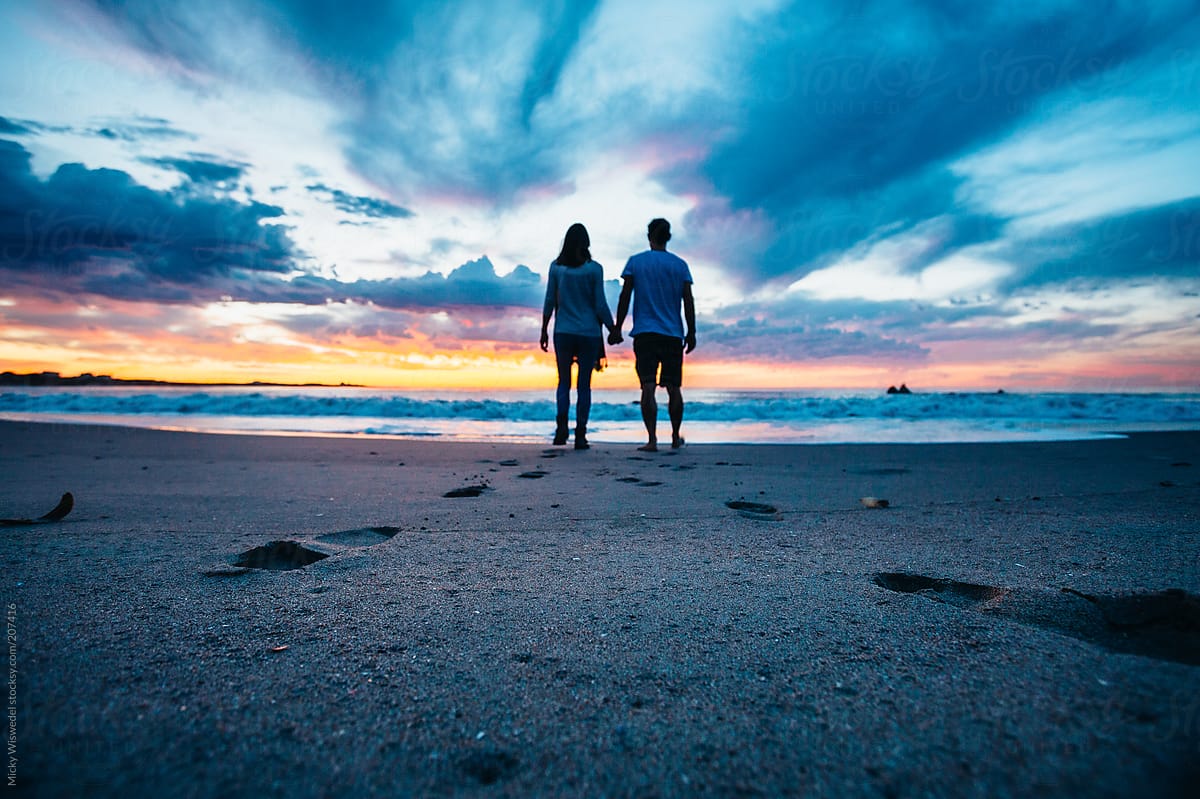 Couple Holding Hands On The Beach At Sunset By Stocksy Contributor