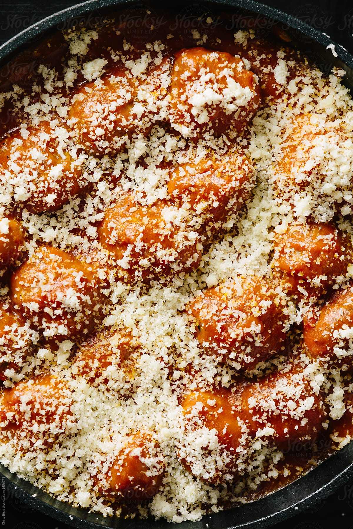 Baked meatballs in pan topped with grated parmesan Italian chees