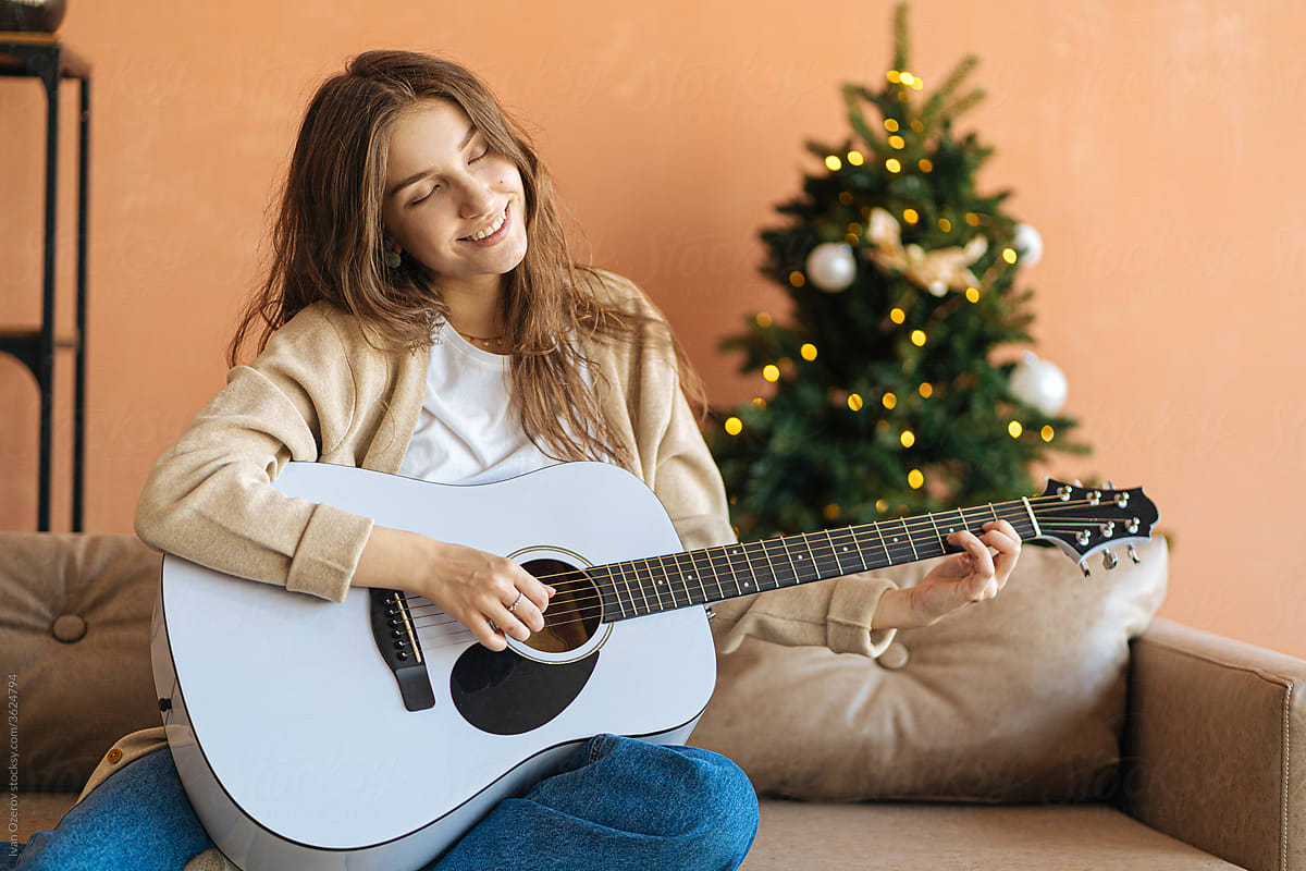 woman playing guitar at home during christmas holidays