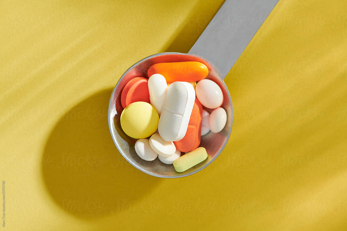 Metal spoon with colored pills, dietary supplements