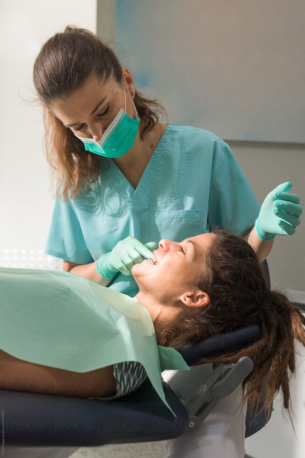 Female dentist fixing dental braces to her patient