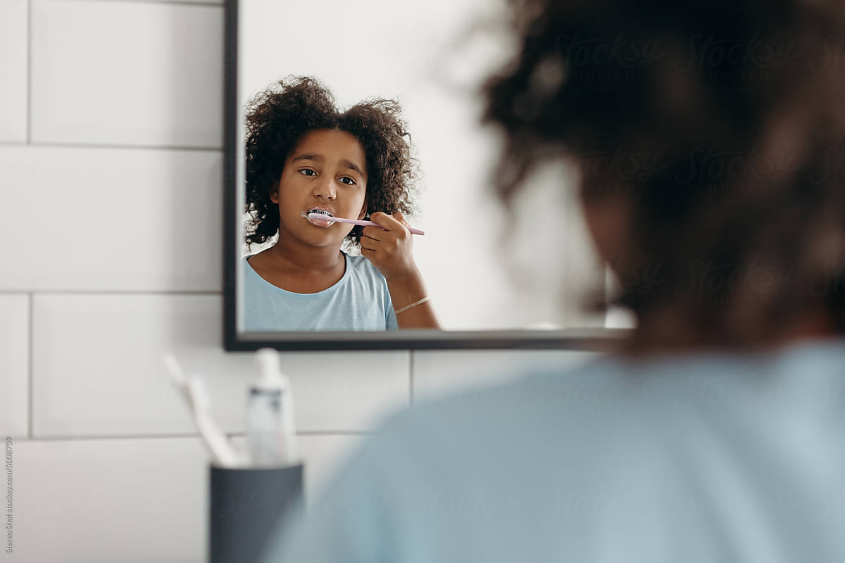 Black child brushing teeth in bathroom