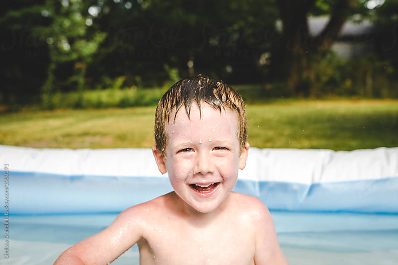 Smiling face of child swimming in backyard pool
