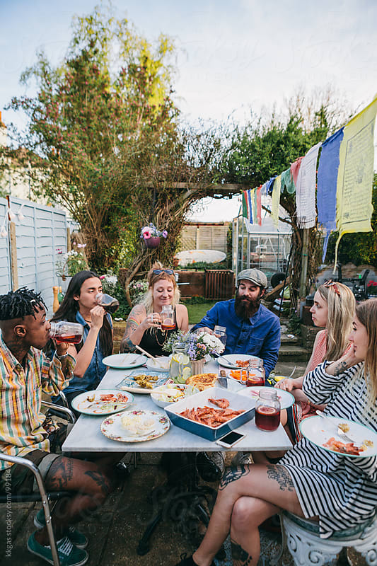 Group of young people having lunch and soft drinks in a garden party