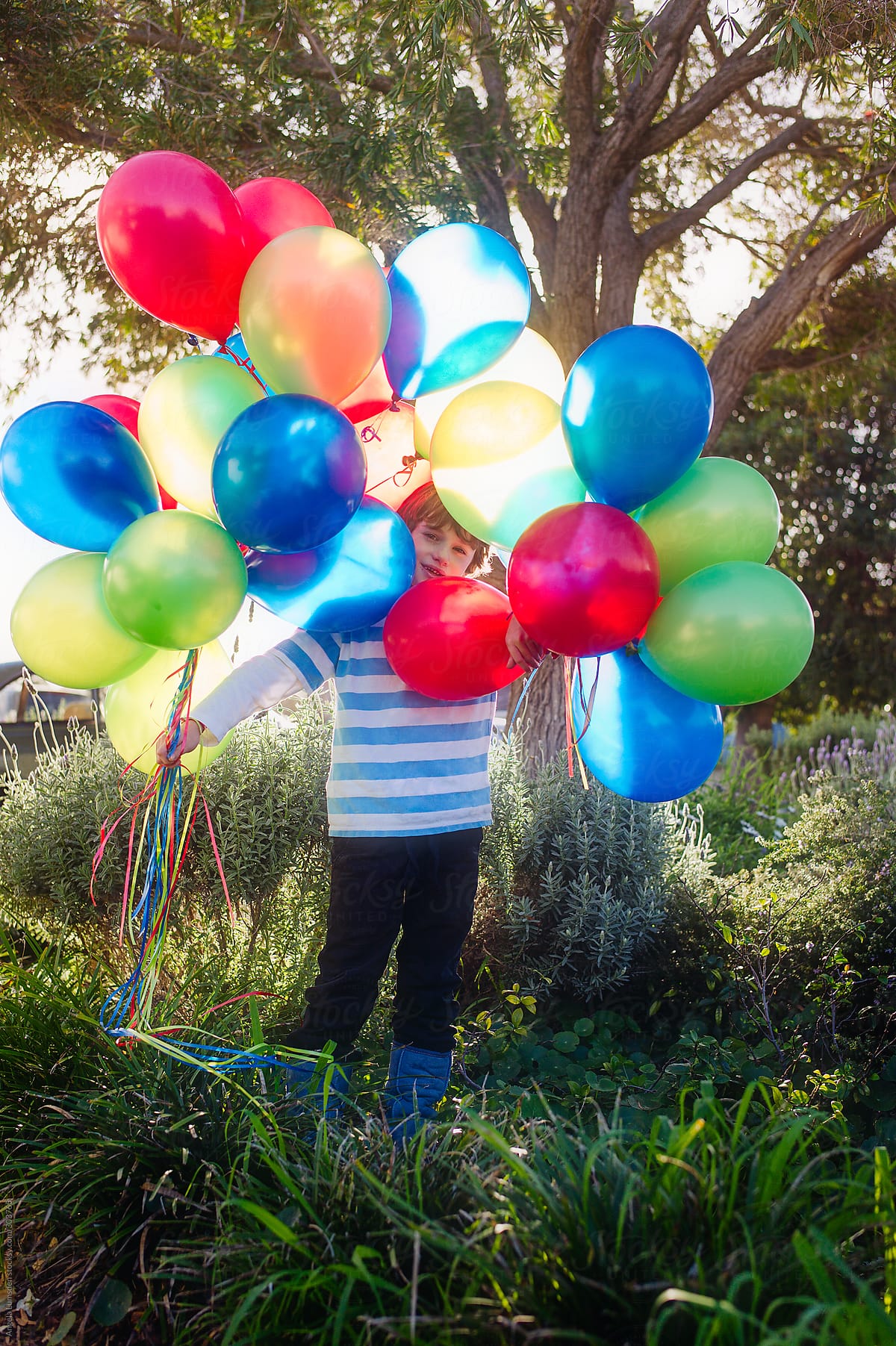 Boy with a large bunch of brightly coloured balloons