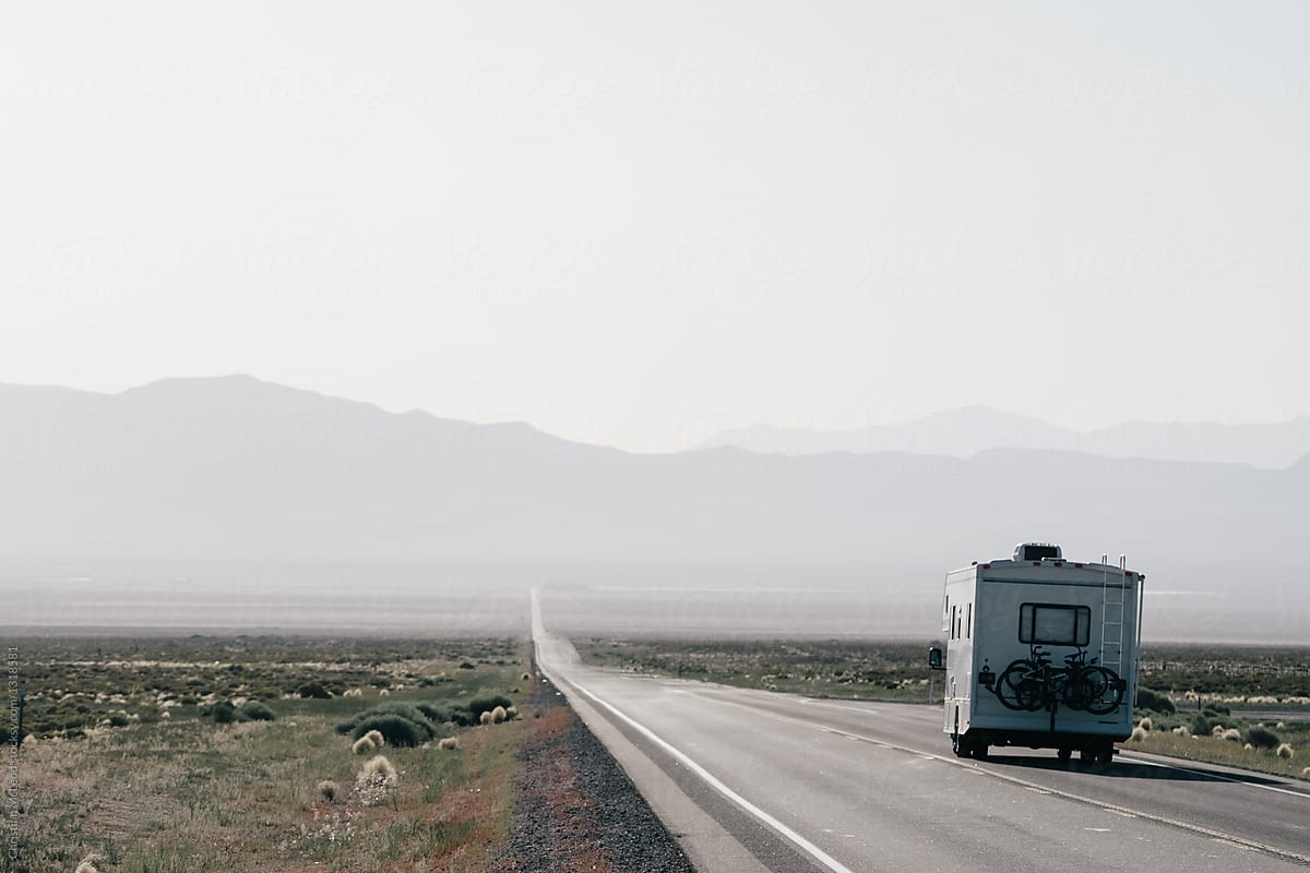 RV drives down a long empty road in the desert