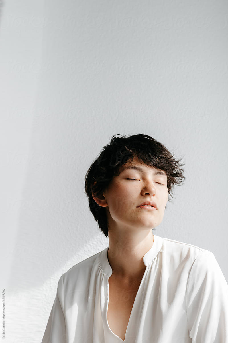 Calm androgynous person with closed eyes against white background